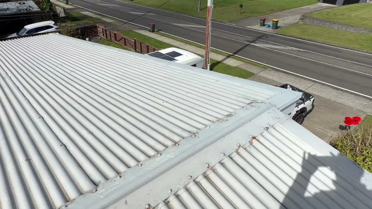 Deteriorated corrugated iron ridge cap and loose lead-head nails in Pukehangi before restoration