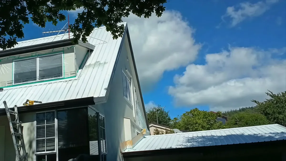 Dormer windows and walls masked for spray protection during steep roof painting